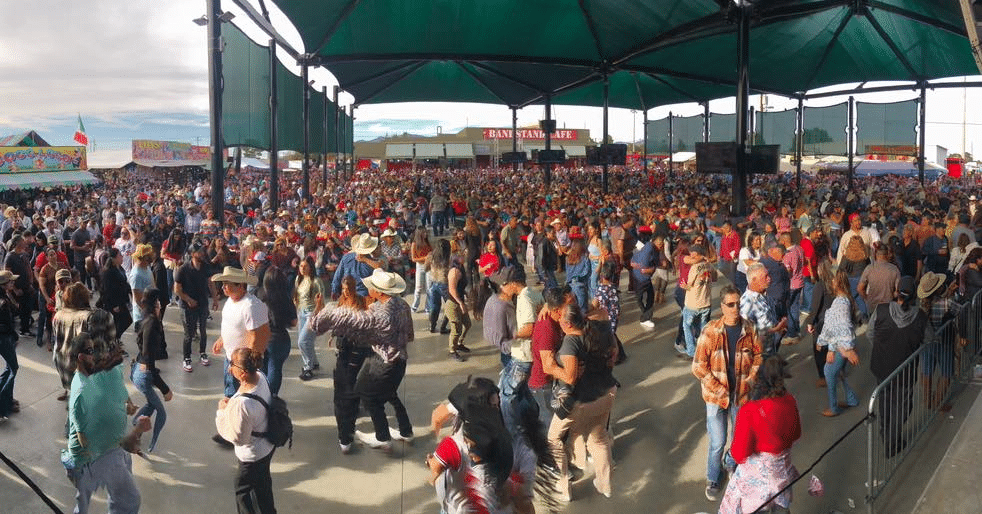 Large crowd underneath a tent at Broadacres marketplace with food booths visible in the background