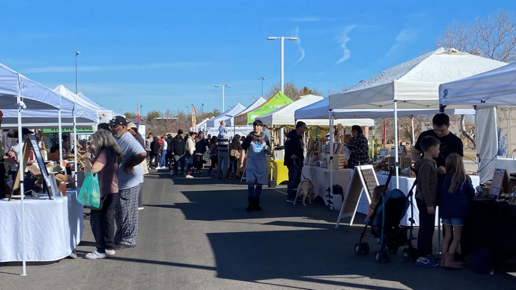 Long row of tents with groups of people shopping at Prevail Marketplace in Cornerstone Park