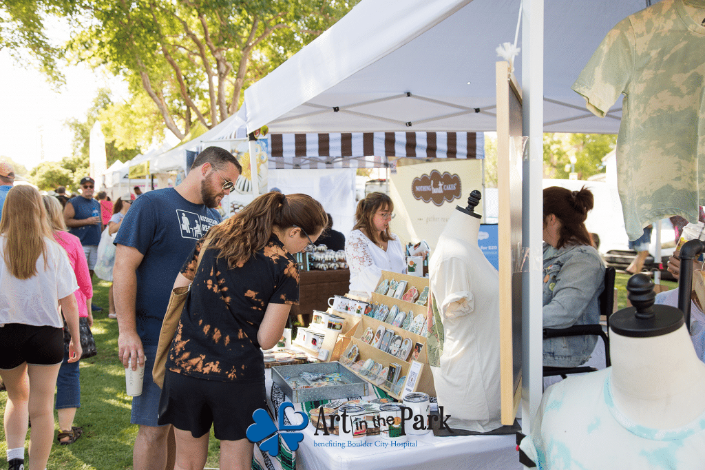 Two people looking at stickers at a booth at Art in the Park in Boulder City